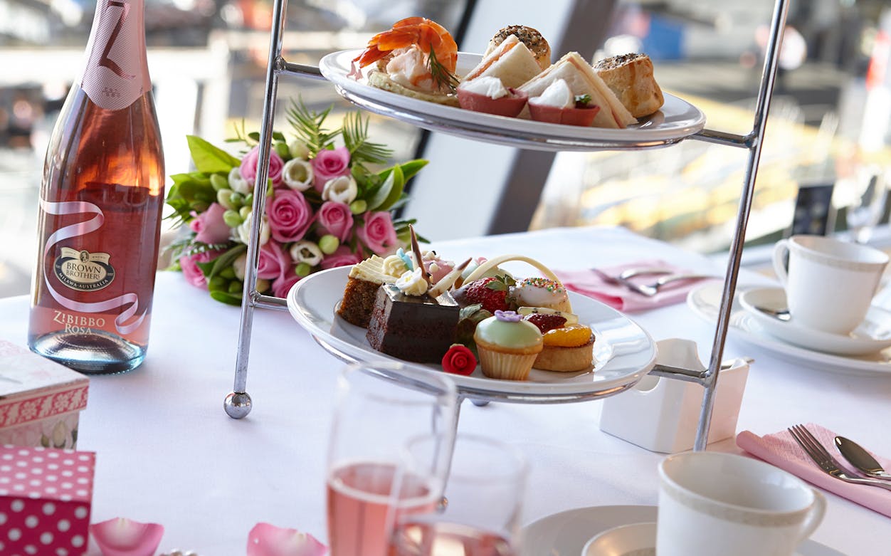 High tea setup with pastries and champagne on a cruise table.