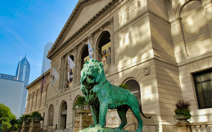 Art Institute of Chicago entrance with iconic lion statue and city skyline.