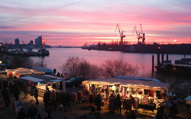 Altona Fish Market at sunset with stalls and harbor cranes in Hamburg.