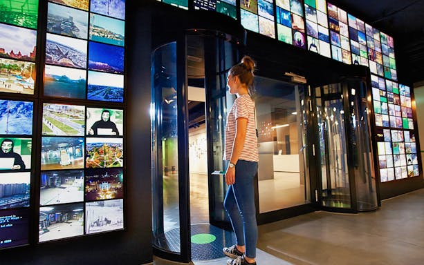Visitor at German Spy Museum Berlin entrance with digital displays.