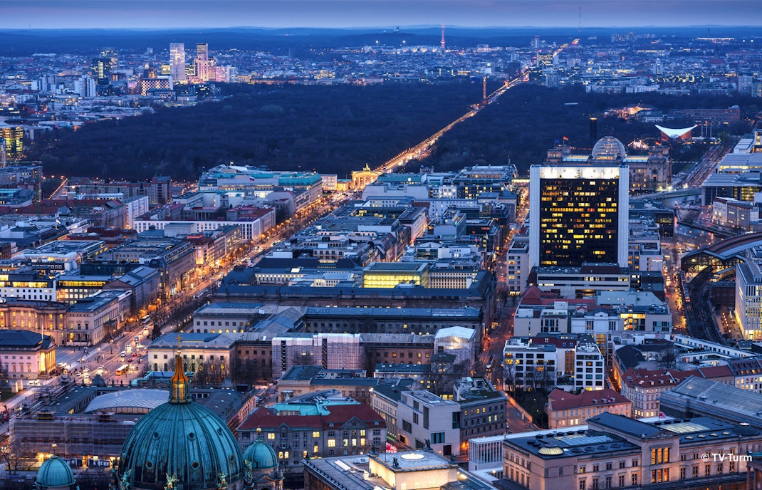 Hell erleuchtete Gebäude und Straßen in Berlin aus der Vogelperspektive bei Nacht