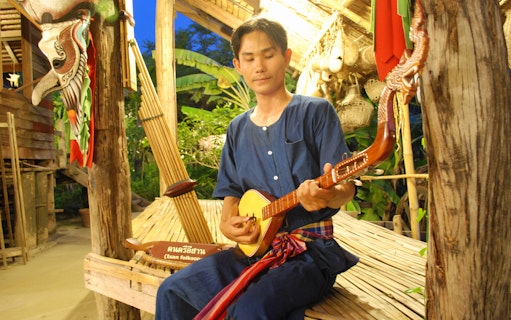 Musician playing traditional Thai instrument at Siam Niramit Bangkok.