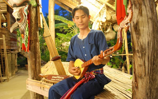 Musician playing traditional Thai instrument at Siam Niramit Bangkok.
