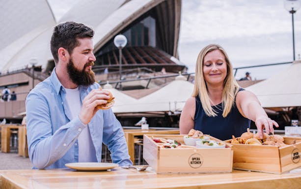 Couple enjoying tasting plates at Opera Kitchen with Sydney Opera House in background.
