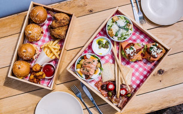 Tasting plates with sliders, fried chicken, and antipasto on a wooden table for Sydney Opera House tour.