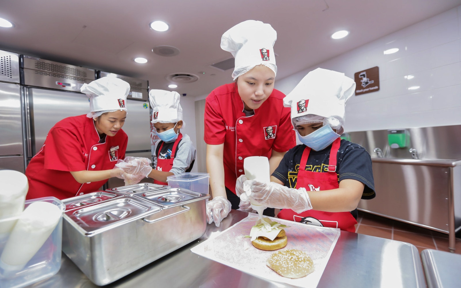 Children in chef hats making burgers at Kidzania Bangkok.
