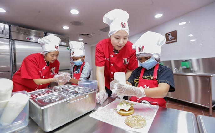 Children in chef hats making burgers at Kidzania Bangkok.