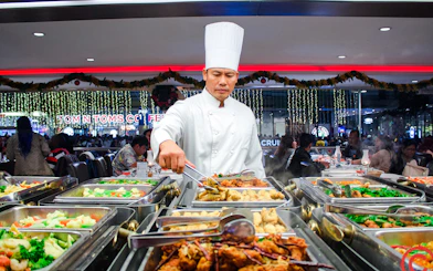 Chef serving buffet on Chao Phraya dinner cruise in Bangkok.