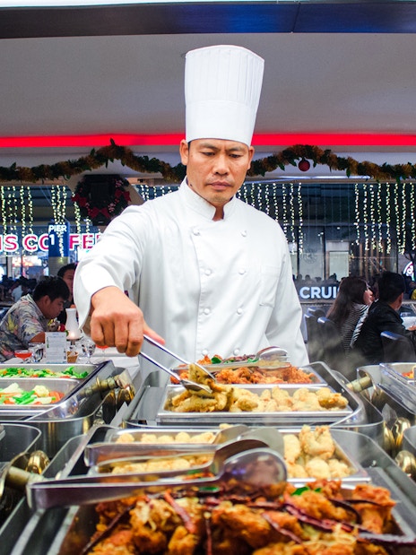 Chef serving buffet on Chao Phraya dinner cruise in Bangkok.