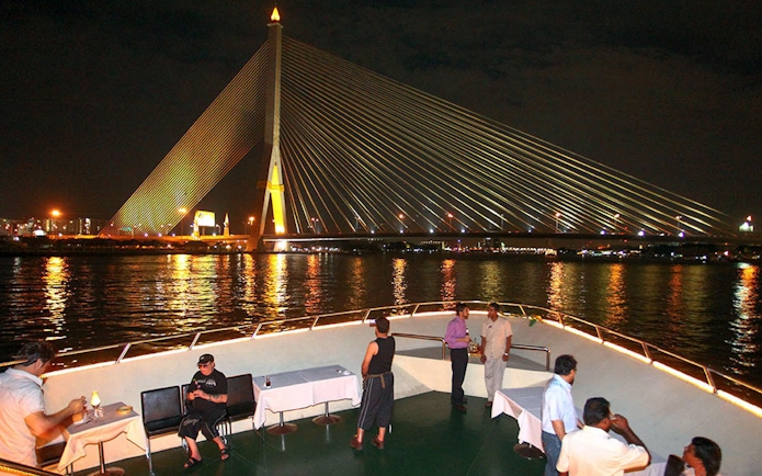 Dinner cruise on Chao Phraya River with view of Rama VIII Bridge, Bangkok.