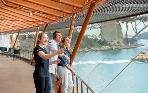Tour group enjoying Sydney Opera House view with guide, overlooking Sydney Harbour.