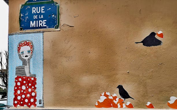 Street art on Rue de la Mire, Montmartre, featuring a stylized figure and birds with hearts.