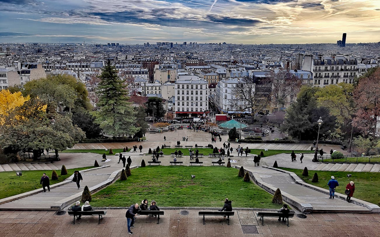 Montmartre view with people walking and Paris skyline in the background.