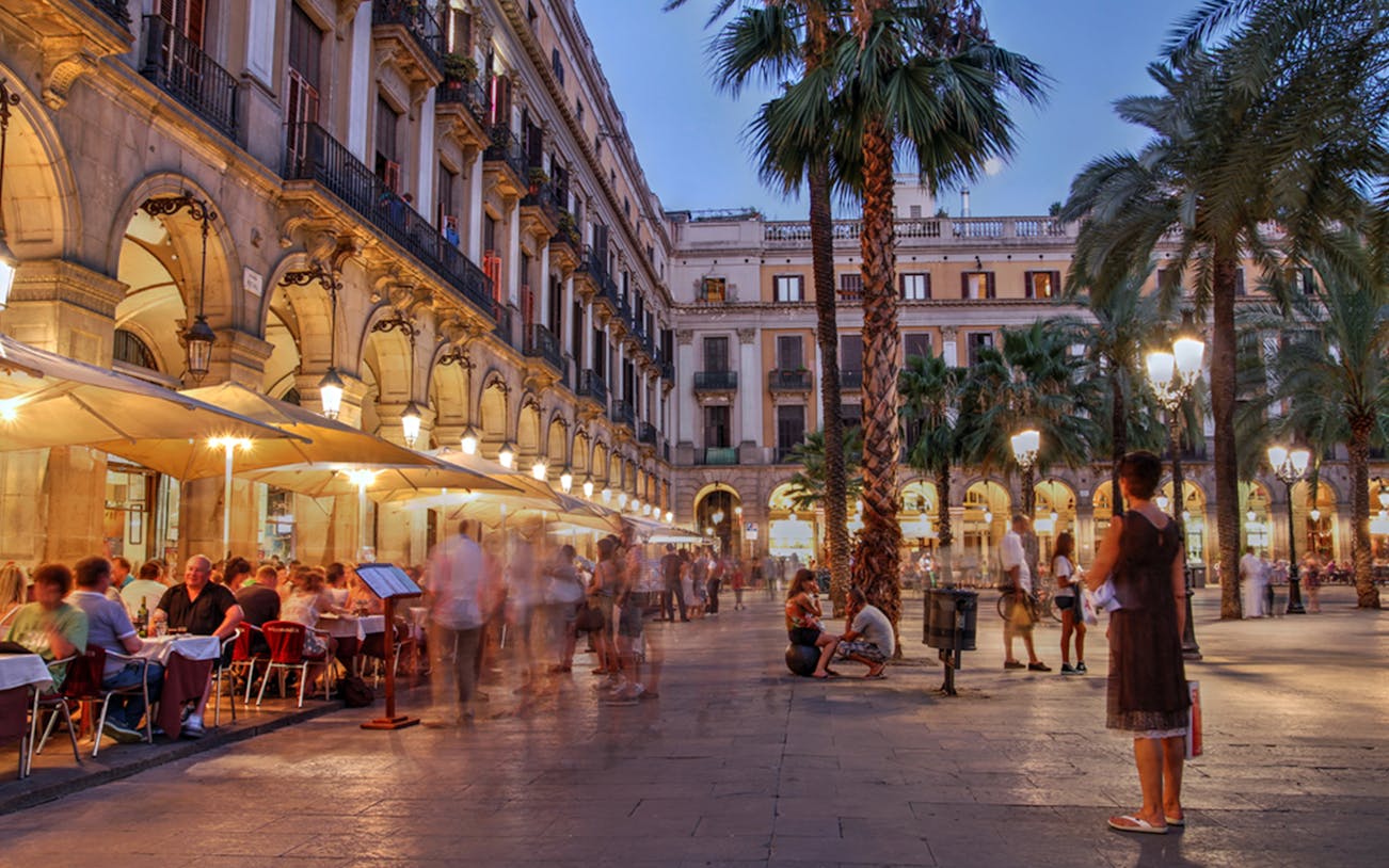Barcelona Gothic Quarter evening scene with people dining outdoors in a historic plaza.