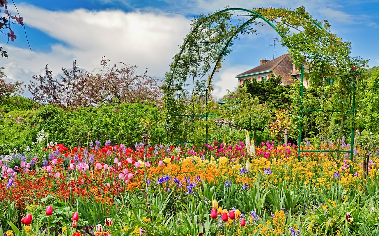 Giverny Monet’s Gardens with vibrant flowers and archway, view from Paris tour.