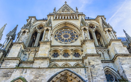 Reims Cathedral facade with intricate Gothic architecture, part of Champagne tour from Paris.