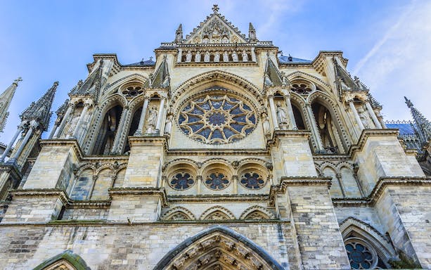 Reims Cathedral facade with intricate Gothic architecture, part of Champagne tour from Paris.