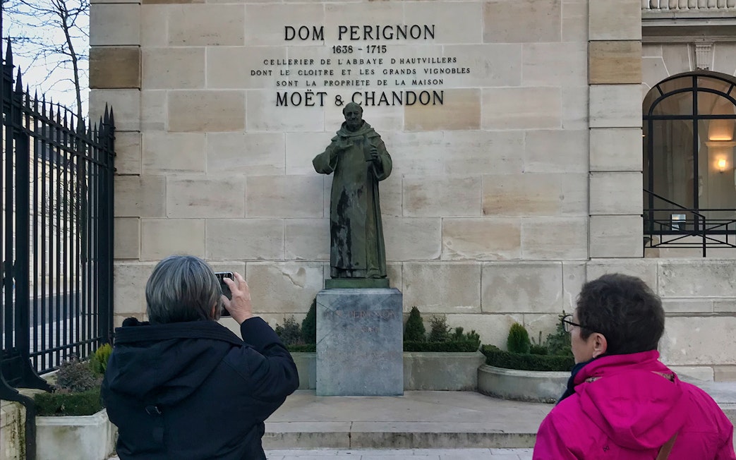 Visitors photographing Dom Perignon statue at Moët & Chandon, Champagne region tour.