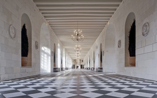 Grand hallway with checkered floor and chandeliers at Chenonceau Castle, France.