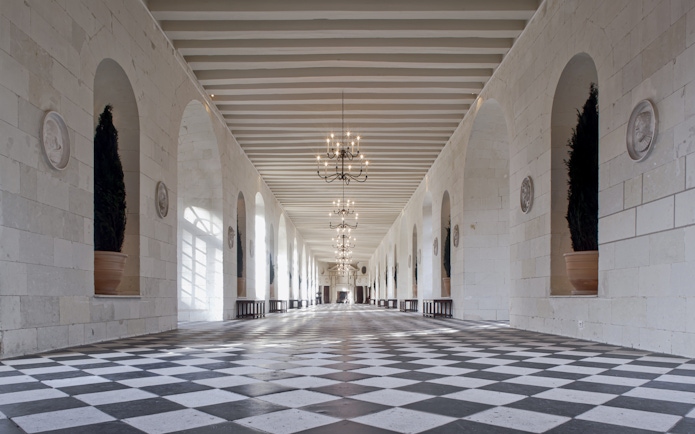 Grand hallway with checkered floor and chandeliers at Chenonceau Castle, France.