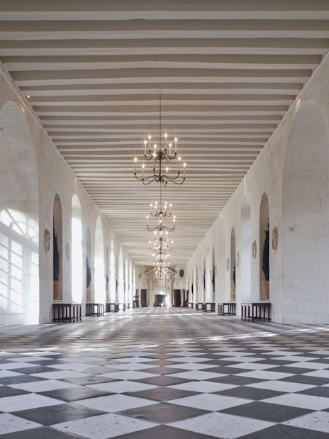 Grand hallway with checkered floor and chandeliers at Chenonceau Castle, France.
