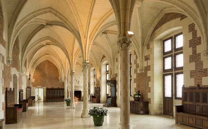 Interior of a vaulted hall in Clos Lucé Castle, featuring ornate columns and a fireplace.