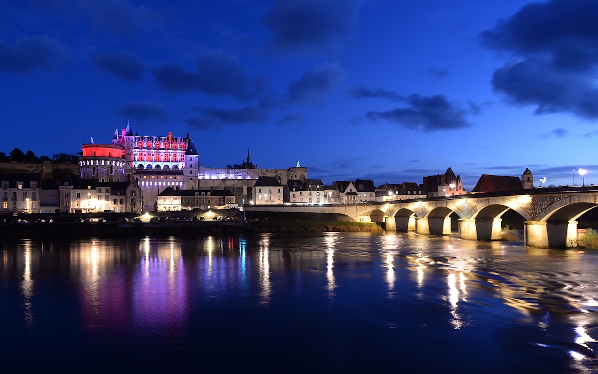Amboise Castle illuminated at night with reflections on the Loire River, France.