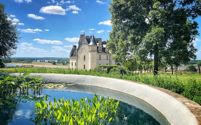 Castle with turret and pond in lush garden, Loire Valley, France.
