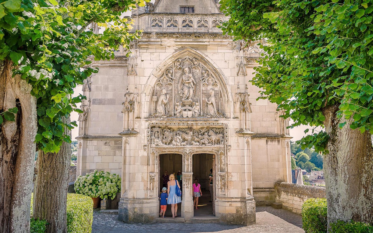 Entrance of Amboise Castle with detailed stone carvings and visitors walking inside.