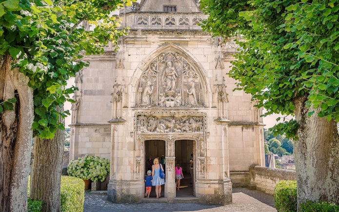 Entrance of Amboise Castle with detailed stone carvings and visitors walking inside.