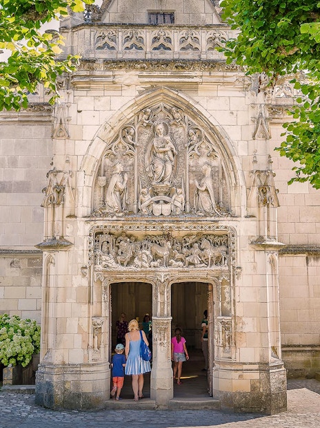 Entrance of Amboise Castle with detailed stone carvings and visitors walking inside.