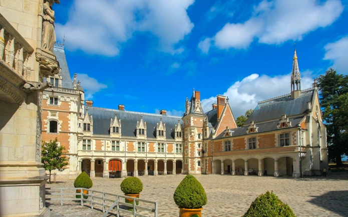 Courtyard of Blois Castle with ornate architecture under a blue sky.