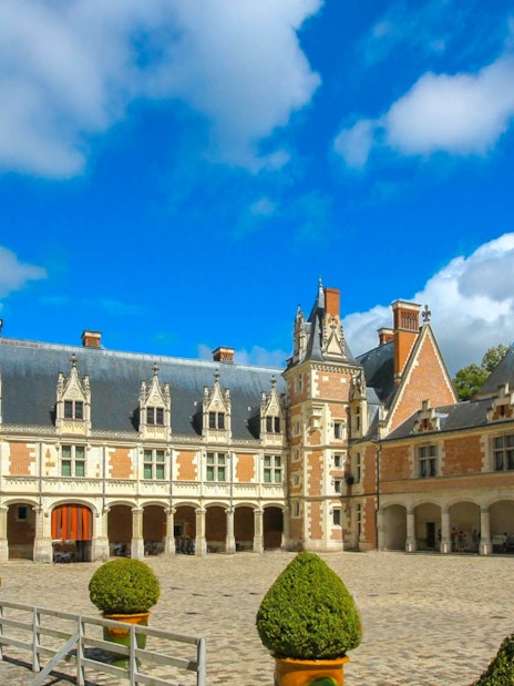 Courtyard of Blois Castle with ornate architecture under a blue sky.