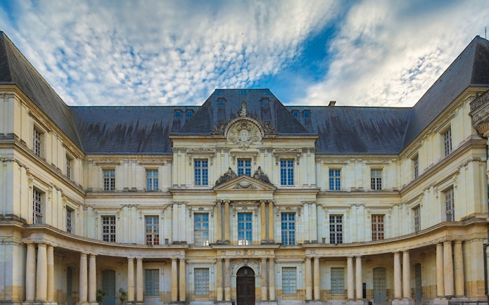 Facade of Château de Blois with ornate architecture under a cloudy sky, Chaumont sur Loire.
