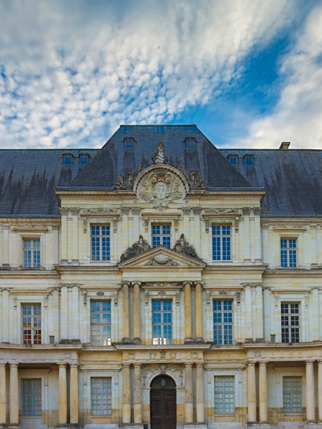 Facade of Château de Blois with ornate architecture under a cloudy sky, Chaumont sur Loire.