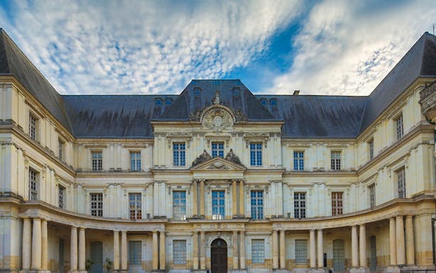Facade of Château de Blois with ornate architecture under a cloudy sky, Chaumont sur Loire.