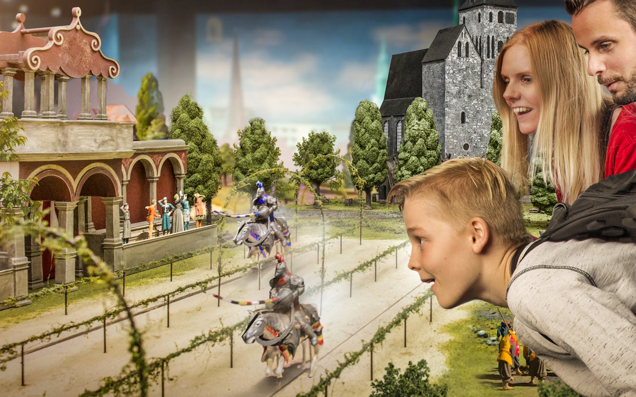 Visitors observing miniature medieval knights at Little BIG City exhibit.