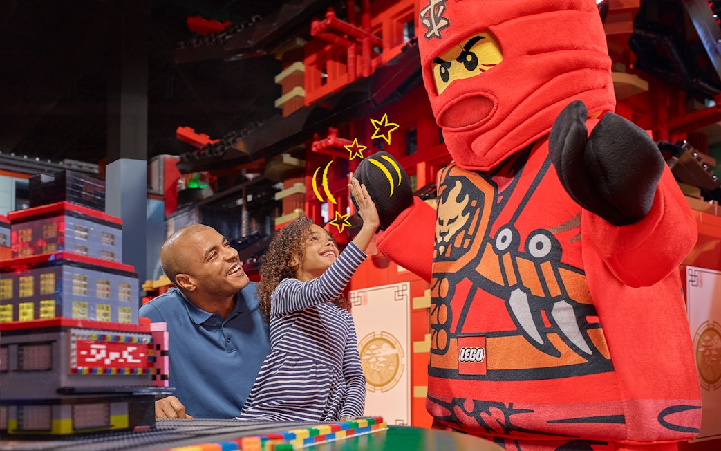 Child high-fiving LEGO character at LEGOLAND Discovery Centre Berlin entrance.