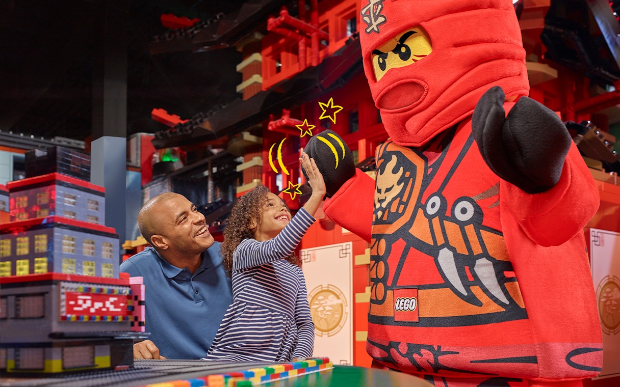 Child high-fiving LEGO character at LEGOLAND Discovery Centre Berlin entrance.