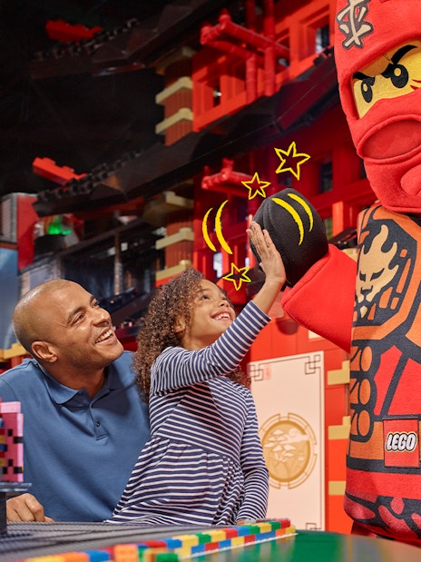 Child high-fiving LEGO character at LEGOLAND Discovery Centre Berlin entrance.