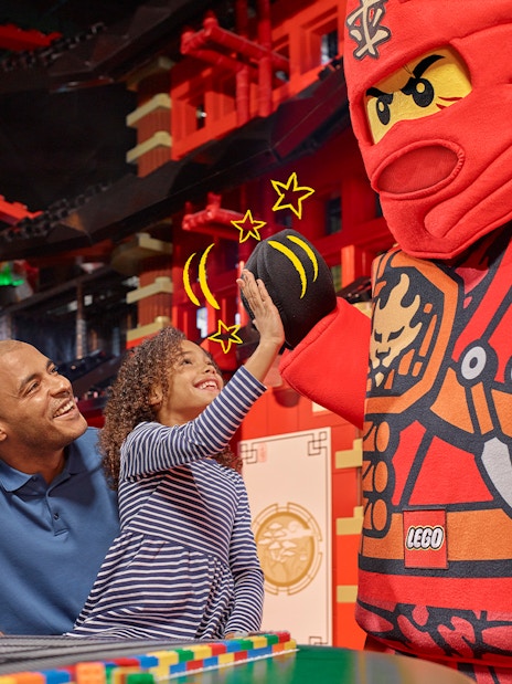 Child high-fiving LEGO character at LEGOLAND Discovery Centre Berlin entrance.