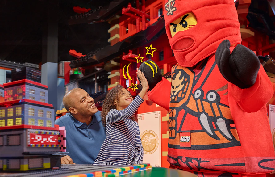 Child high-fiving LEGO character at LEGOLAND Discovery Centre Berlin entrance.