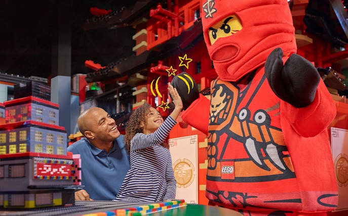 Child high-fiving LEGO character at LEGOLAND Discovery Centre Berlin entrance.
