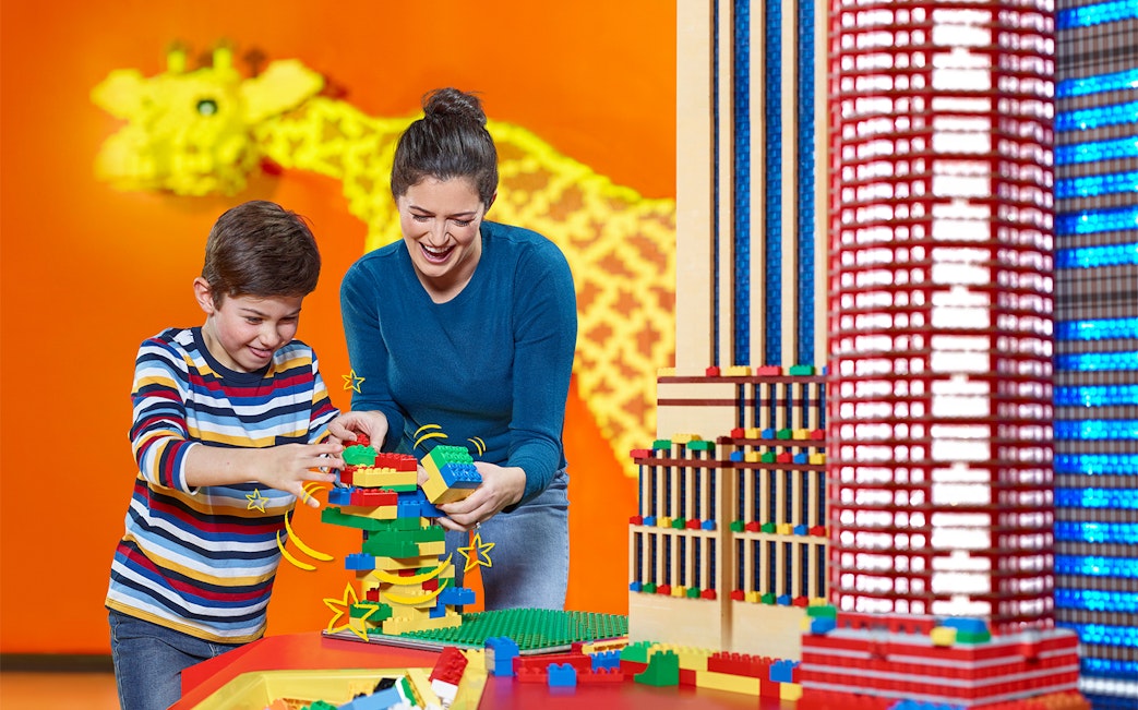 Child and adult building with LEGO at Berlin attraction.