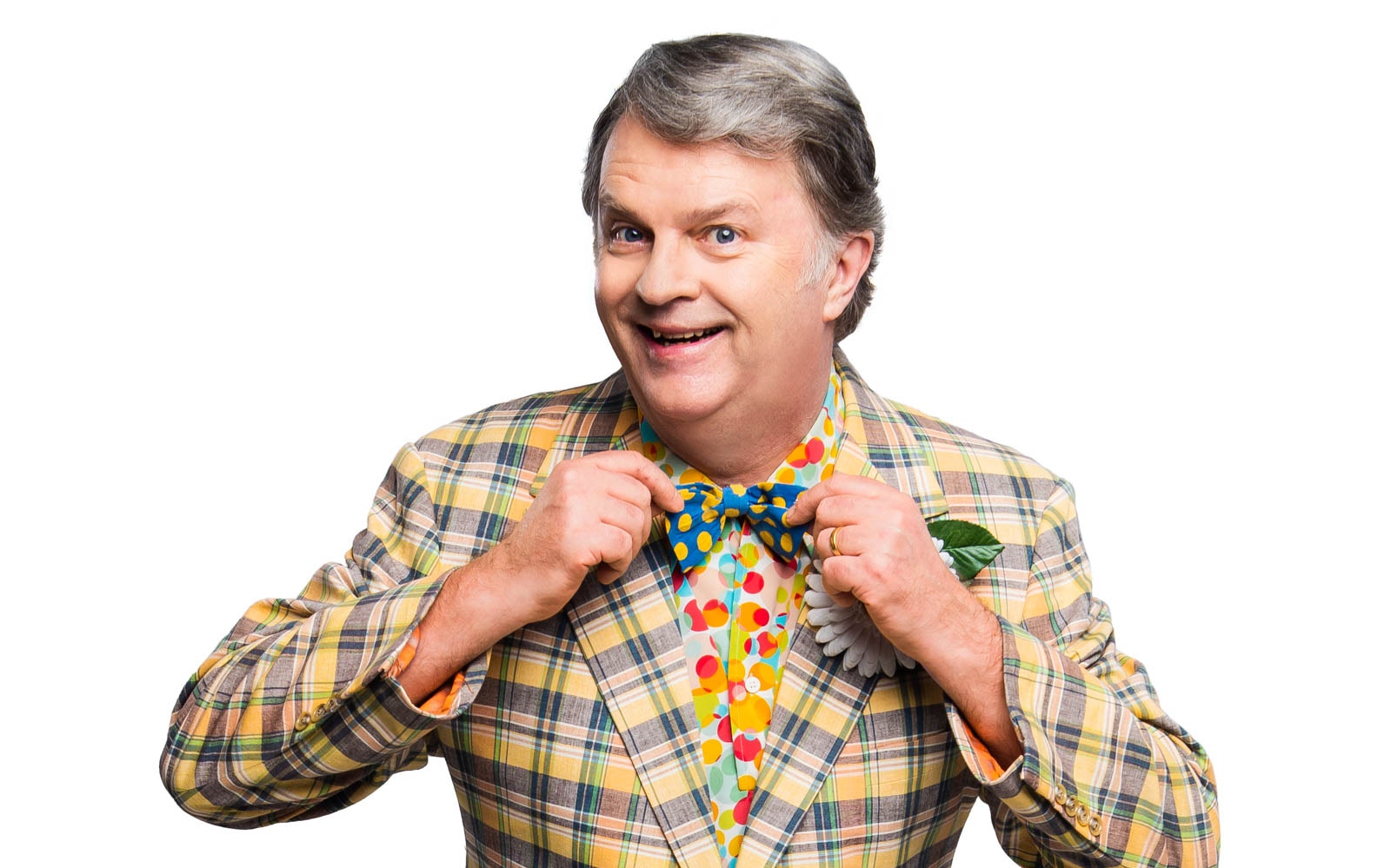 Man in colorful plaid suit adjusting bow tie, related to Hairspray musical.