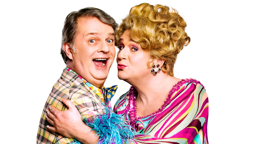 Two performers in colorful costumes from the musical "Hairspray.