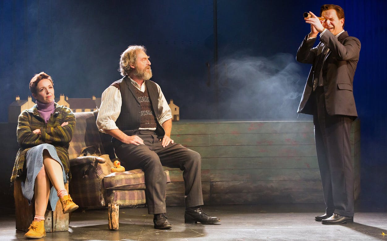 Stage scene from "Local Hero" with three actors, one using a telescope.