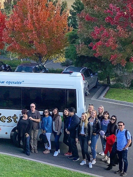 Group of tourists beside a tour bus in Yarra Valley during a guided gourmet tour.