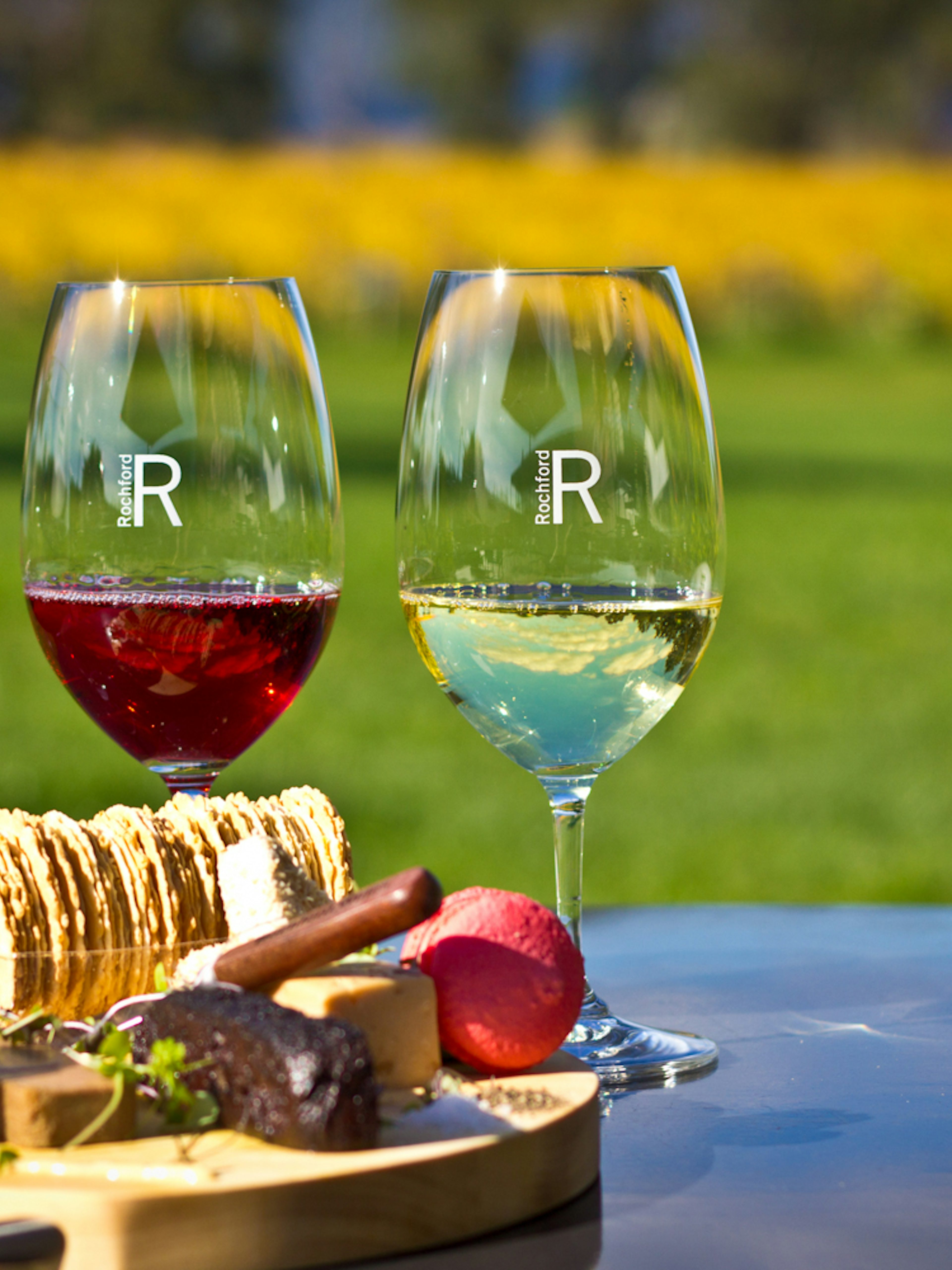 Three wine glasses with red and white wine, cheese platter at Yarra Valley vineyard.