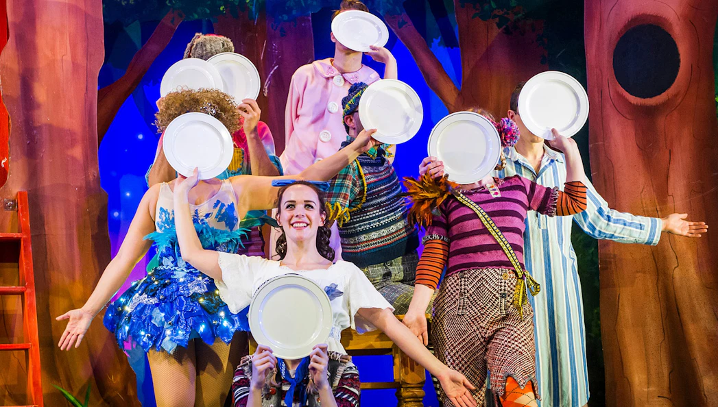 Performers on stage holding plates in a scene from "Peter Pan Goes Wrong.
